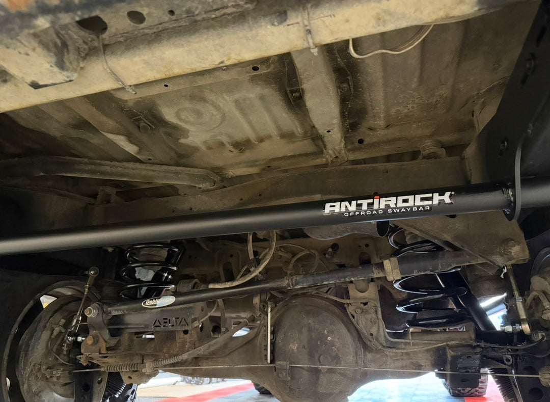 BPF 80 Series Land Cruiser RockJock AntiRock Frame Mounting Plates installed beneath a Toyota Land Cruiser with visible sway bar suspension and axle