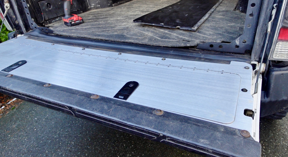 BPF 2005-2015 Toyota Tacoma Tailgate Panel installed on the open tailgate of a truck, featuring a durable, light-colored metal surface with black latch components.