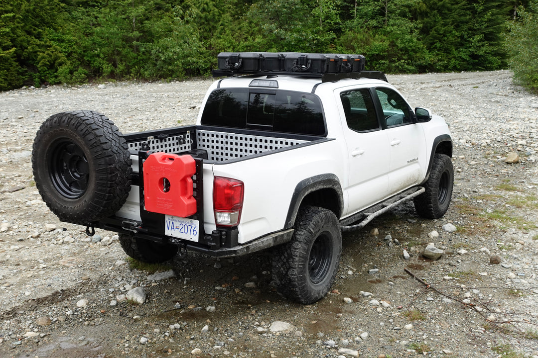 White off-road truck equipped with BPF Universal Pelican Vault V700 Case Mounting brackets holding gear on the roof rack and rear bed, parked on rocky terrain.