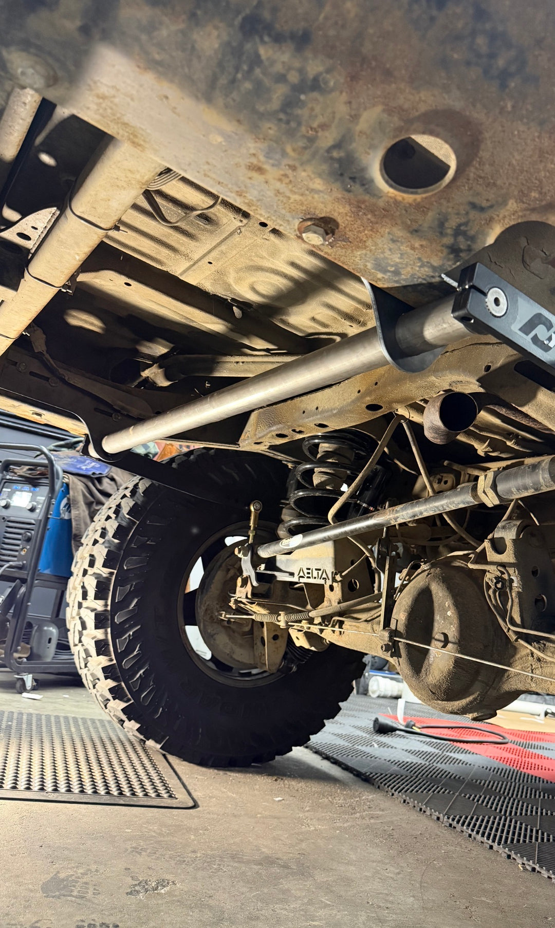 BPF 80 Series Land Cruiser RockJock AntiRock Frame Mounting Plates installed beneath a rugged Land Cruiser chassis with visible suspension components and frame reinforcement