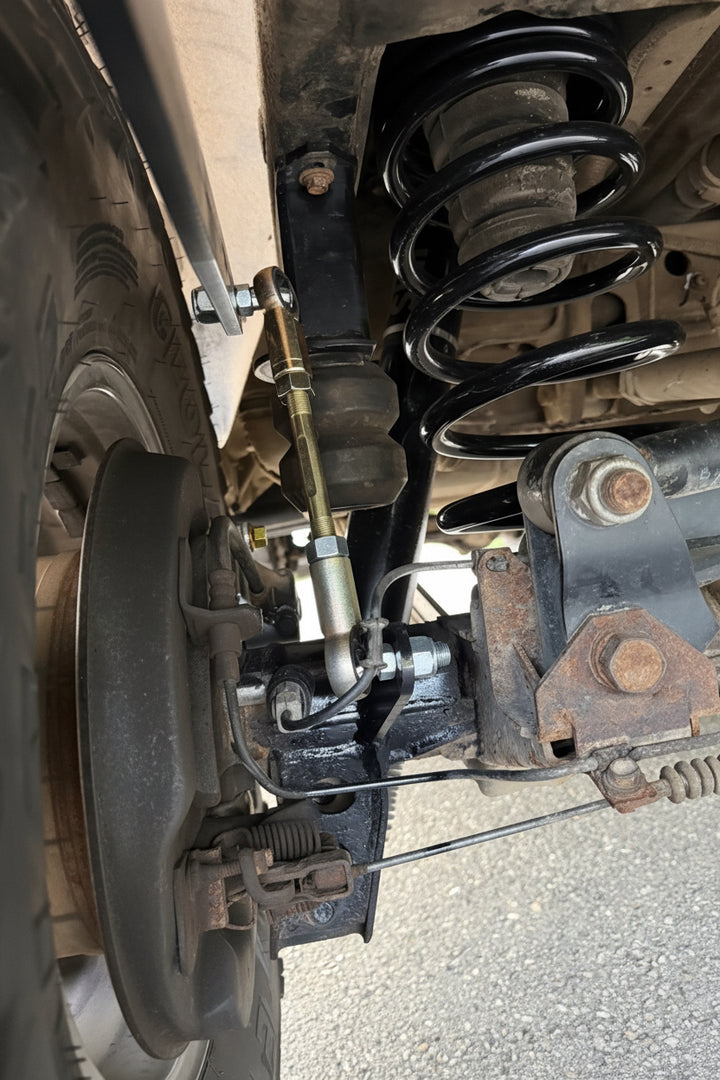 BPF 80 Series Land Cruiser RockJock AntiRock Frame Mounting Plates shown with a coil spring and suspension components beneath the vehicle