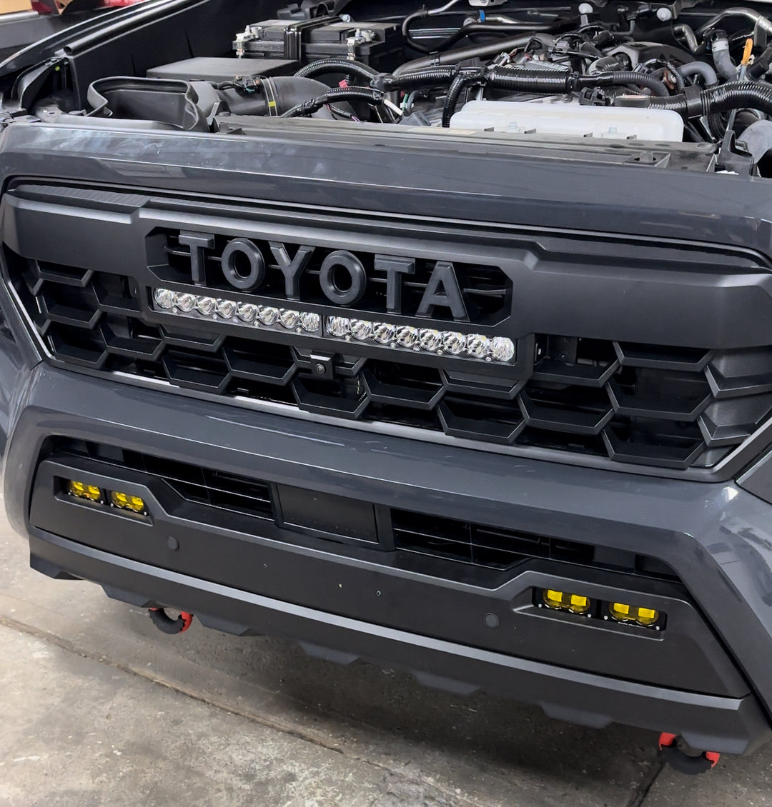 Close-up of a black 2024 Trailhunter Grille with BPF letters installed on a truck front, featuring honeycomb-style grille design and integrated LED light bar.