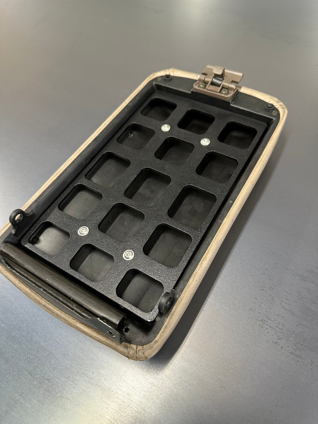 BPF 80 Series Land Cruiser/LX450 Center Console Molle Panel featuring a black powder coated molle mounting grid inside a beige center console lid on a gray surface.