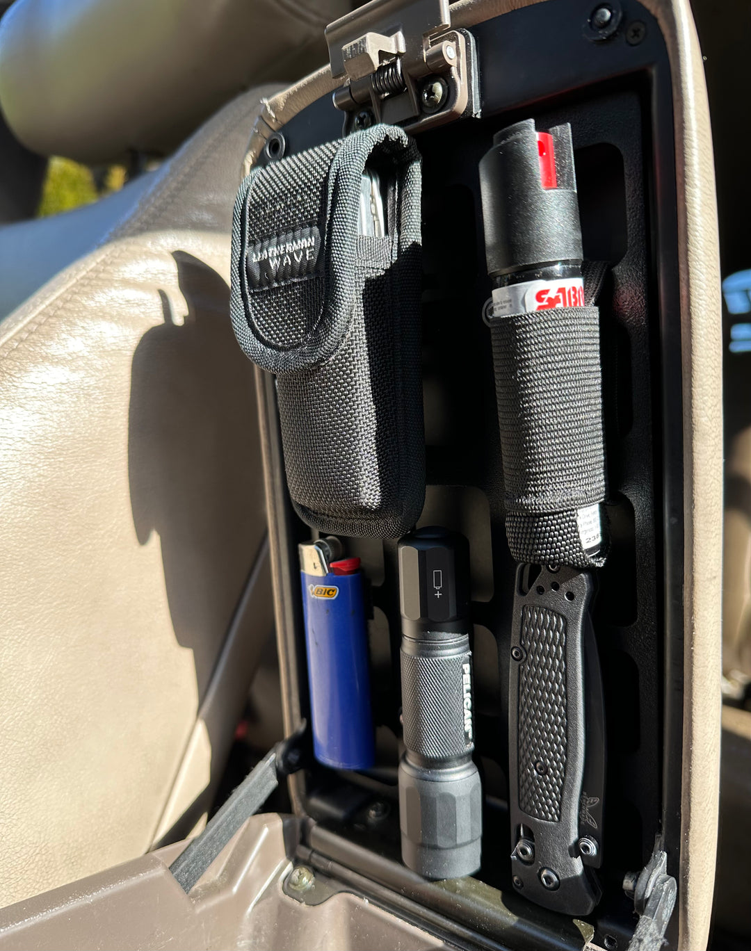 BPF 80 Series Land Cruiser/LX450 Center Console Molle Panel holding various tools and accessories including a multitool pouch, lighters, flashlight, and folding knife securely inside the vehicle console.