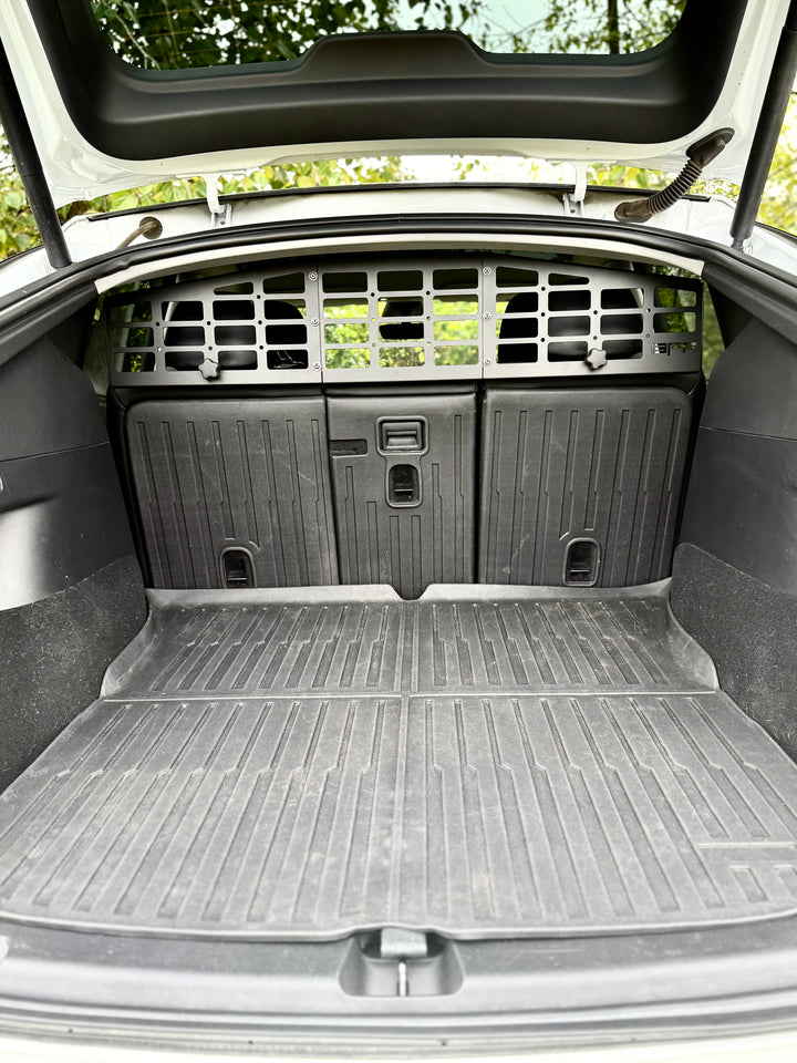 Cargo area of a Tesla Model Y equipped with a black BPF Molle Style Pet Barrier Tesla Model Y 2020-CURRENT installed behind the rear seats, featuring molle panels and a sturdy rubber cargo mat.