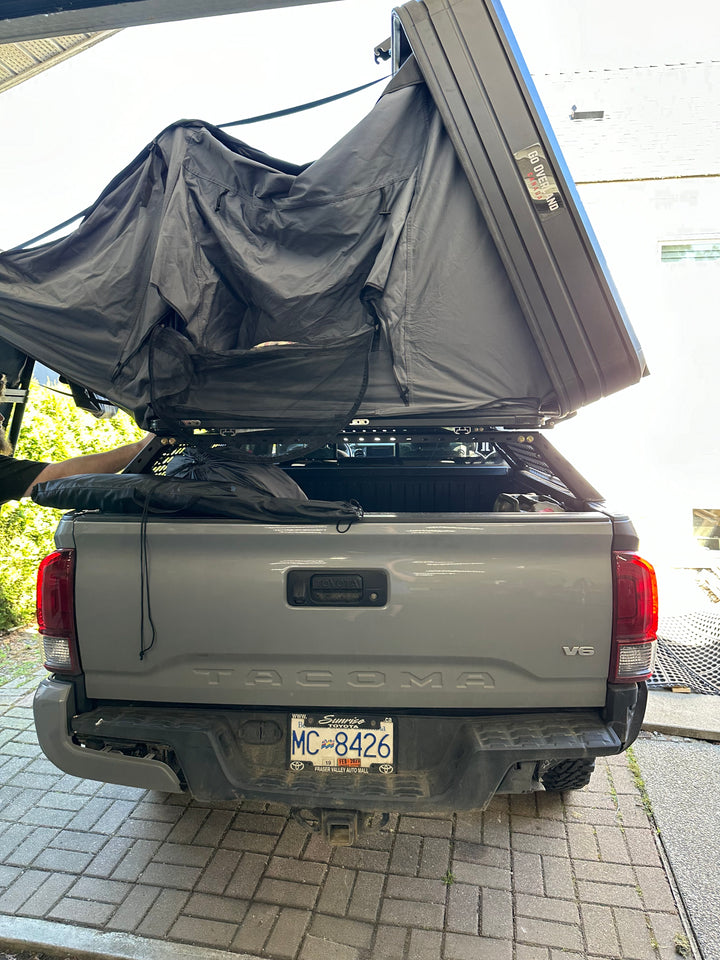 05-26 Tacoma Bed Rack fits 2nd,3rd and 4th gen Tacomas mounted on a gray Tacoma truck with a rooftop tent partially unfolded over the truck bed.