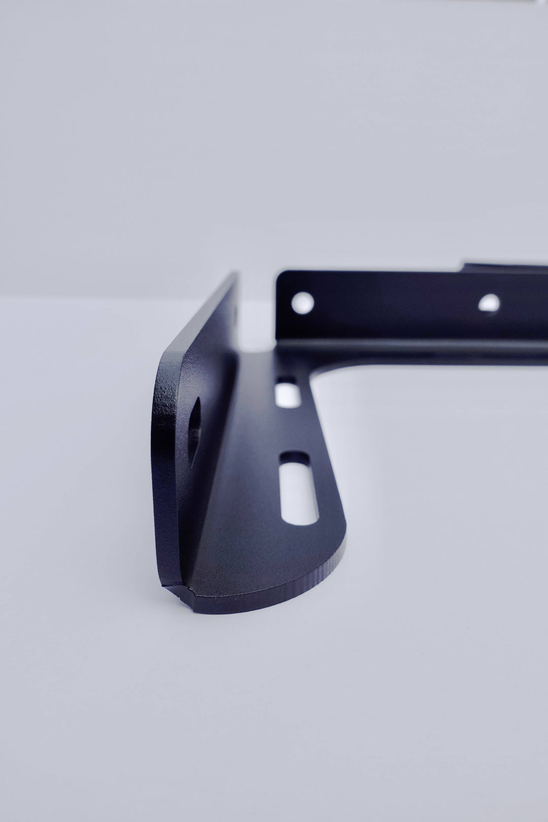 Close-up of a black powder-coated metal bracket component from the BPF 2005-2023 Toyota Tacoma Bed Stiffeners showing precise CNC fabricated mounting holes and smooth edges.