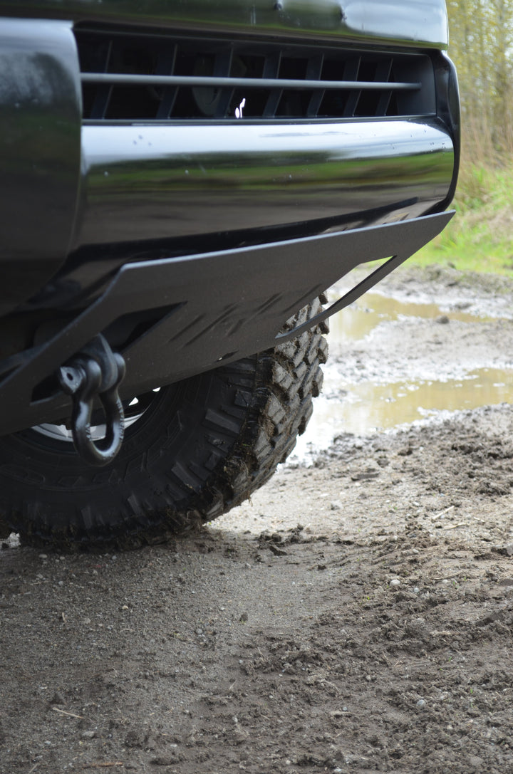 Close-up of a heavy duty BPF 2005-2023 HD Tacoma Recovery Tow Hook Passenger Side mounted on a black off-road vehicle front bumper with rugged tire and muddy terrain background.