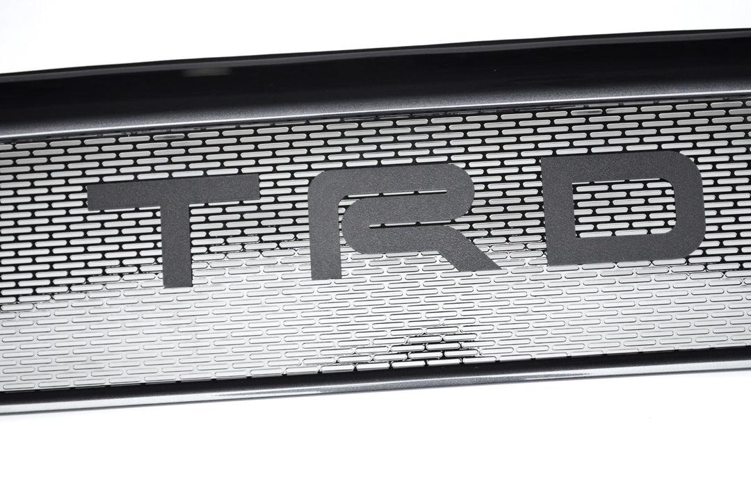 Close-up of the BPF 2012-2015 Toyota Tacoma Mesh and Lettering showcasing a black mesh grille with bold TRD lettering for enhanced truck front-end styling and durability.