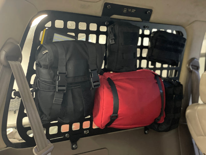 BPF 1990-1997 Toyota Land Cruiser Storage Panels installed inside vehicle, showing black and red gear bags attached to powder-coated molle panel for organized overlanding storage.