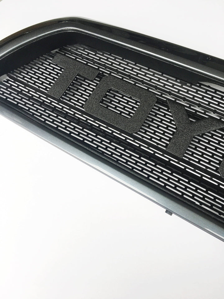 Close-up view of a black textured BPF 03-09 Toyota 4runner Grill with bold raised letters and a precision-cut grill mesh design.
