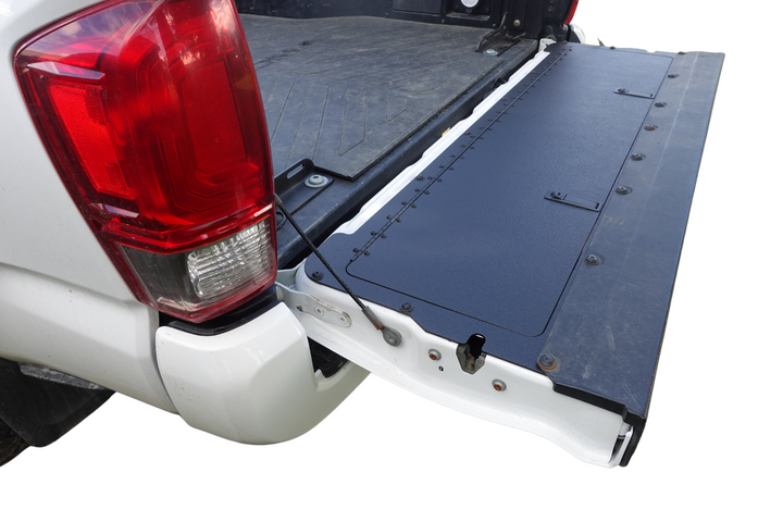 BPF 2016-2023 Toyota Tacoma Tailgate Panel installed on an open white pickup truck tailgate, featuring a durable textured black surface designed for OEM fitment and heavy-duty use.