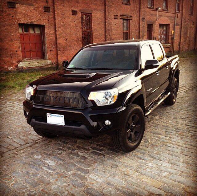 Black Toyota Tacoma truck with a rugged BPF Completed 2012-2015 Toyota Tacoma Grill installed, featuring a mesh-style design and bold Toyota lettering on the front.