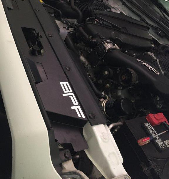 Engine bay view of a black BPF 12-15 Toyota Tacoma Cooling Panel installed near the radiator support, featuring bolt-on design and durable powder-coated finish.