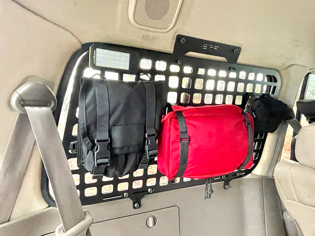 BPF 1990-1997 Toyota Land Cruiser Storage Panels installed inside vehicle rear, featuring black powder-coated molle panel with attached black and red gear bags for overlanding storage.