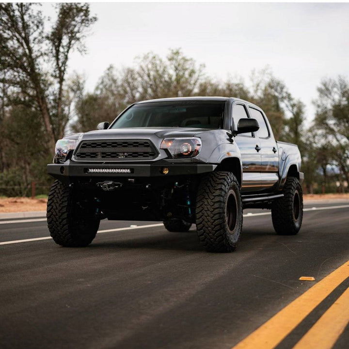 Silver Toyota Tacoma truck equipped with a rugged BPF 2012-2015 Toyota Tacoma Grill, featuring CNC fabricated grill mesh and aftermarket off-road enhancements.
